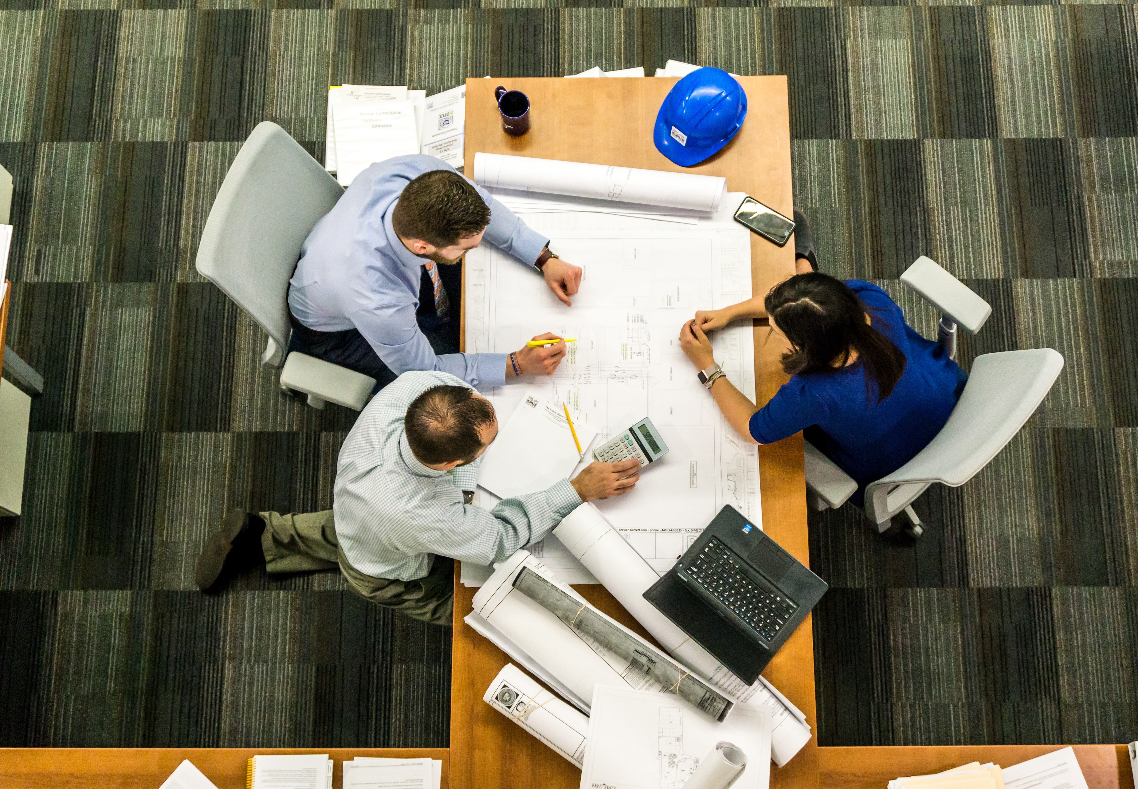 Picture of three people at a meeting table discussing a project.